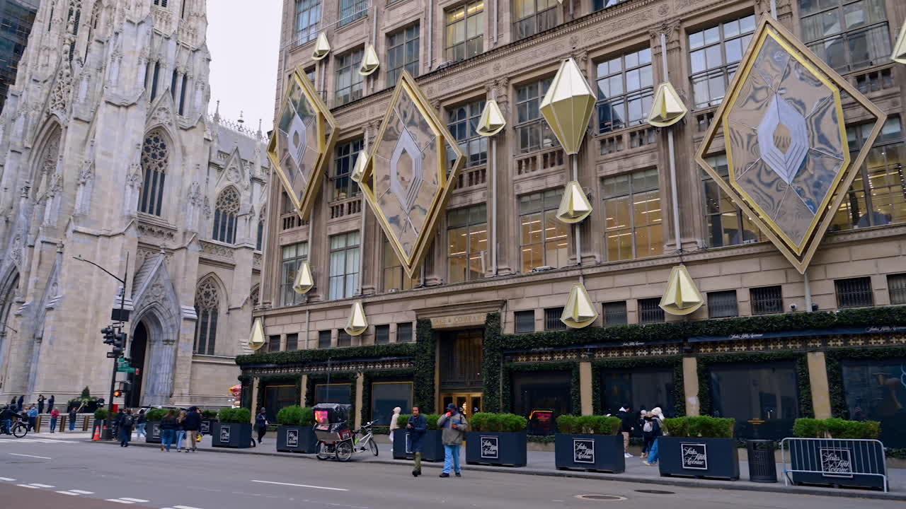 New York, USA, 6 November 2025: Saks Fifth Avenue department store chain with light decoration on the façade. Stunning building of St. Patrick's Cathedral at backdrop. New York USA