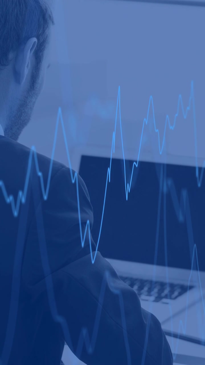Video verticale: Analista che analizza il portatile alla scrivania mentre un flusso di dati modifica una sovrapposizione di grafici finanziari.