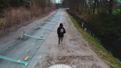 AERIAL-chasing-man-running-through-forest-looking-for-freedom