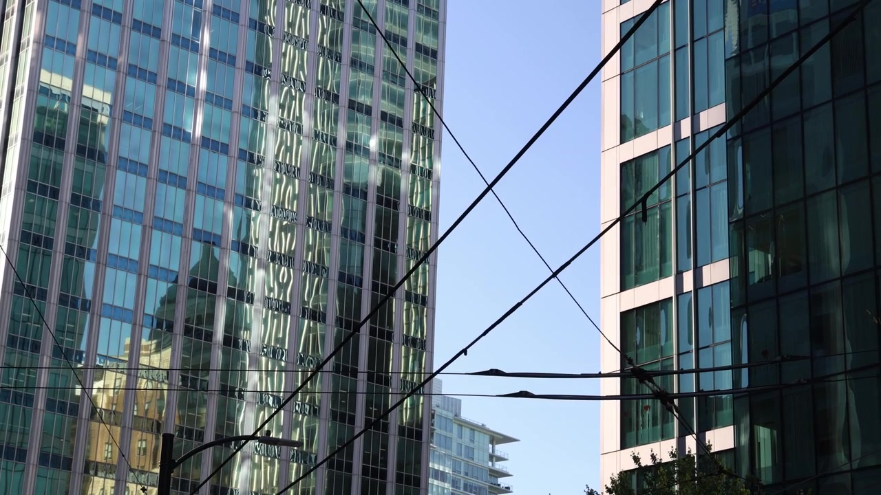 Arranha-céus modernos de vidro e fios elétricos aéreos de ônibus, fundo urbano
