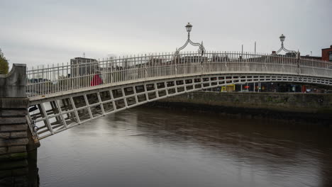 Lapso-De-Tiempo-Del-Puente-De-Medio-Centavo-Con-Personas-Cruzando-El-Río-Liffey-Durante-El-Día-Nublado-En-La-Ciudad-De-Dublín-En-Irlanda