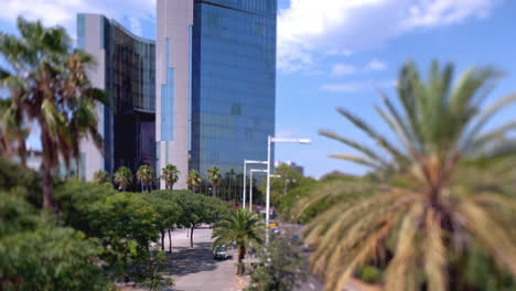 barcelona mirrored glass skyscraper with clouds in the sky and wind blowing palm trees