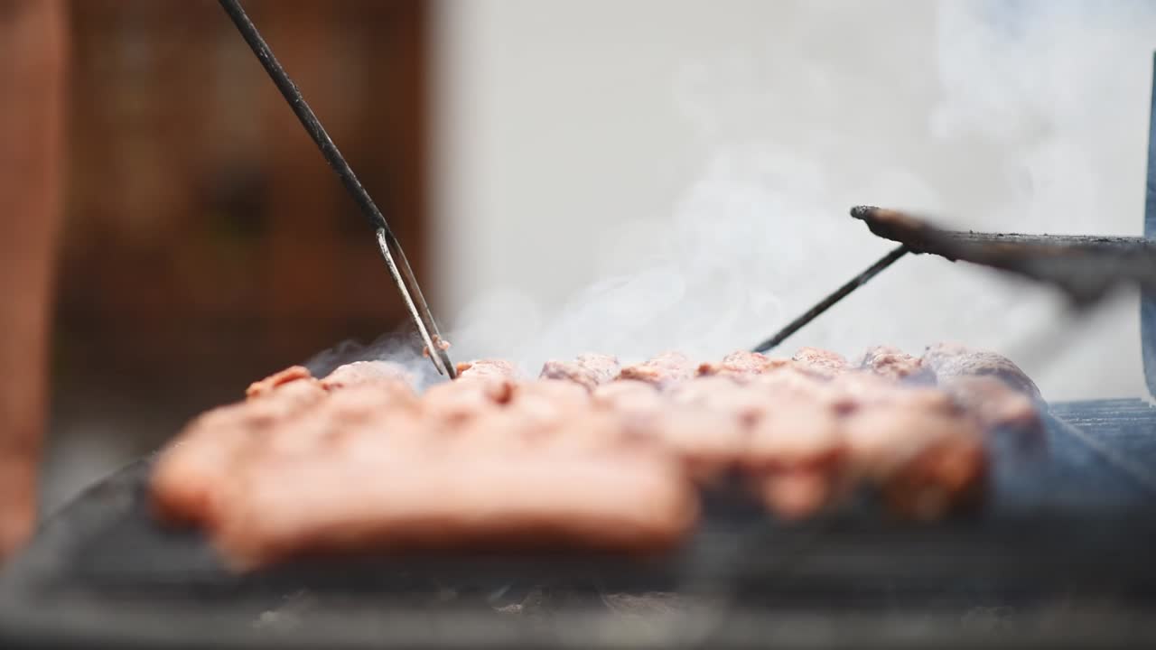Man preparing sausage on the grill using carving fork. Slow motion shot