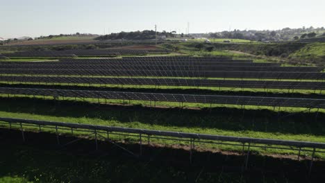 Low-backwards-flight-over-solar-panels-on-solar-farm,-zero-emission-source