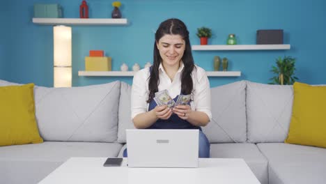 mujer mirando la computadora portátil contando dinero.