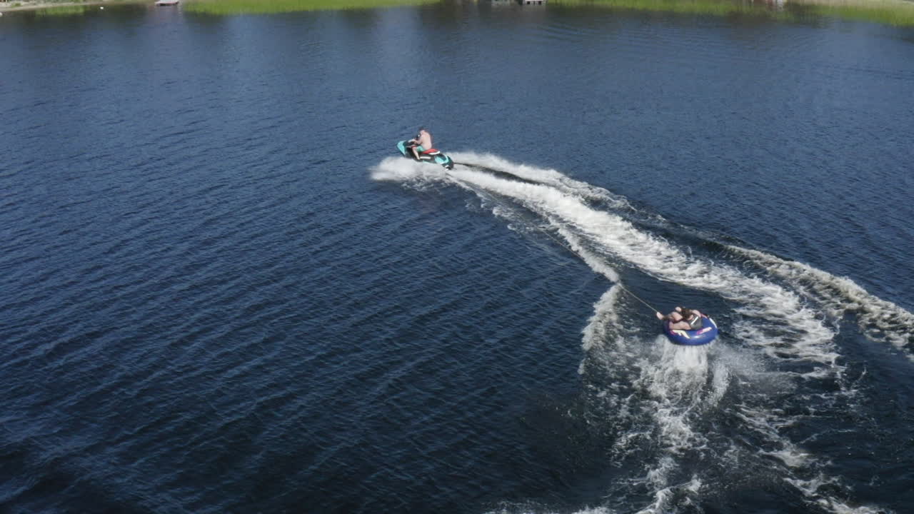 뜨거운 여름날 스웨덴의 호수에서 제트 스키와 링고를 타는 젊은이들