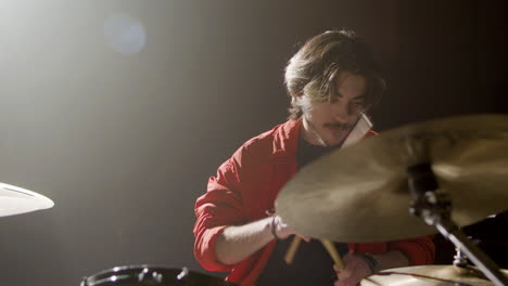 young male drummer playing drums at music studio