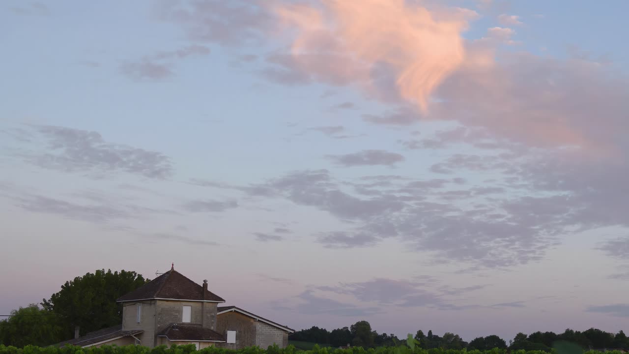 A serene view of a farmhouse beneath a colorful twilight sky with scattered clouds.