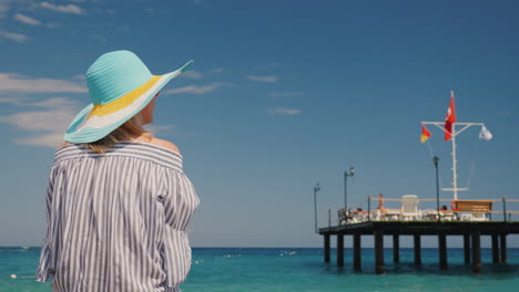 A-Woman-Admires-The-Beautiful-Sea-Rear-View-It-Stands-Near-The-Pier-With-A-Raised-Turkish-Flag-Rest-