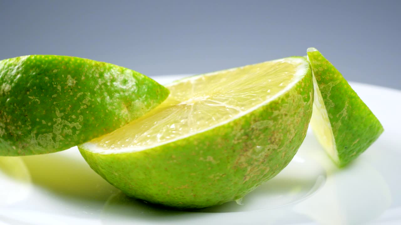 una rebanada de limón verde está girando lentamente en el estudio con los detalles.