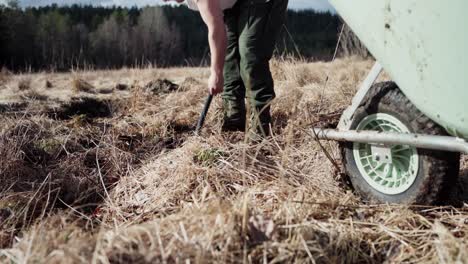 man with shovel digging soil on field for garden use