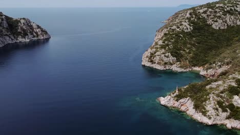 aerial drone flight over blue ocean with rocky coastline during sunny day in greece