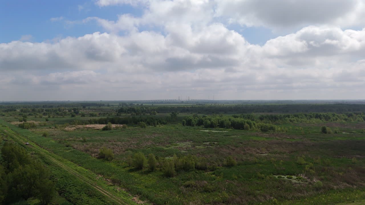 Stunning aerial view of wetlands, forests, and fields stretching towards horizon under cloudy sky, showcasing diverse ecosystem and natural beauty