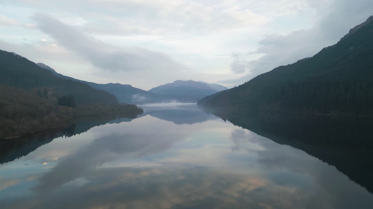 Aerial Lower of Water Reflecting Mountains And Surronding Clouds