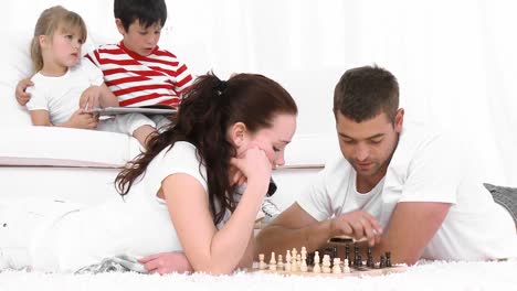 pareja joven jugando al ajedrez en la sala de estar