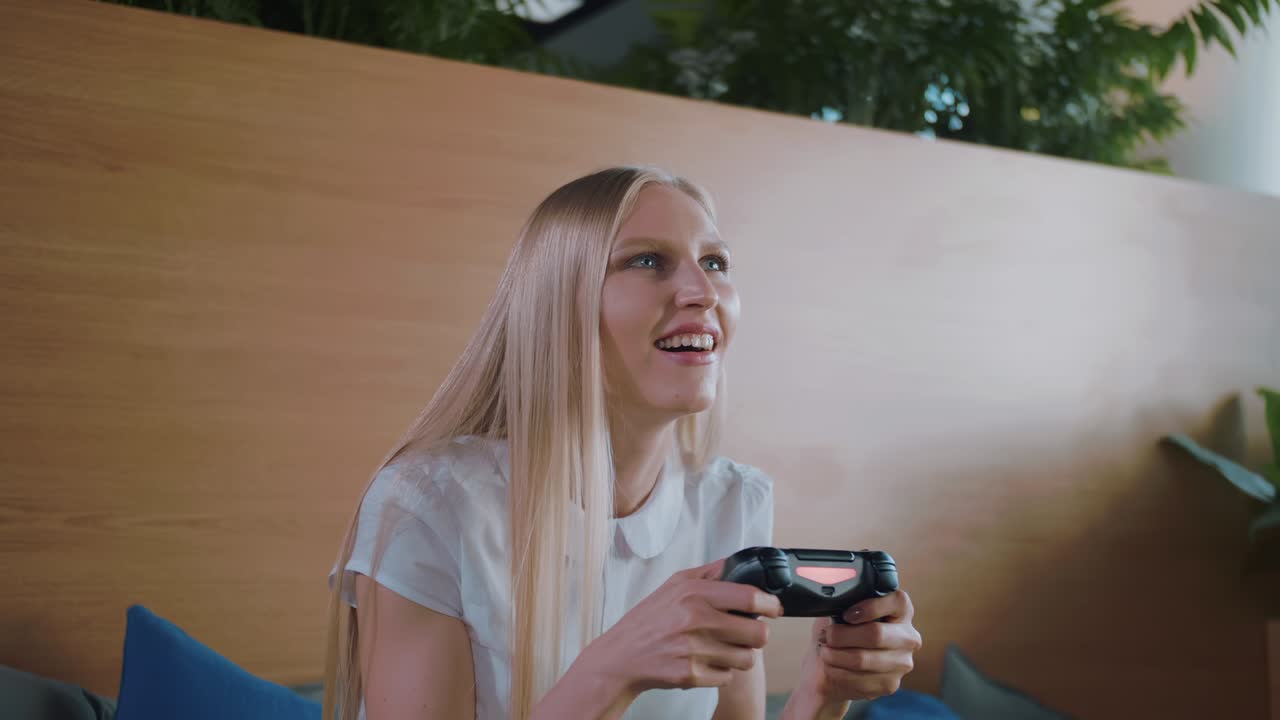 donna che gioca e si rilassa in un ufficio moderno. giovane donna formale in gonna che si rilassa sul divano in un'area ricreativa contemporanea dell'ufficio e gioca a videogiochi con il gamepad