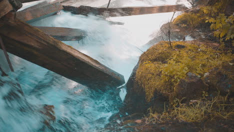 Rauschende-Stromschnellen-Krachen-Im-Herbst-Gegen-Große-Beschädigte-Holzbalken-Mit-Moosbedeckten-Felsen.-4k-Prores