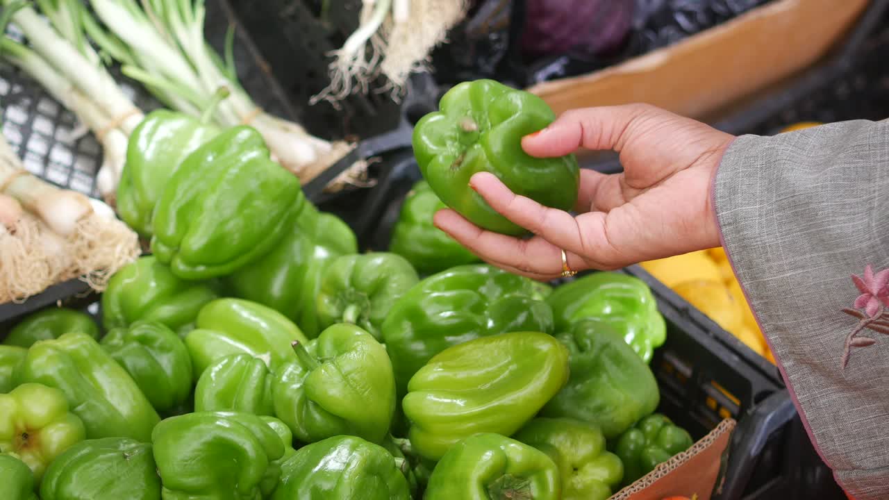 mujer comprando pimientos verdes en un mercado