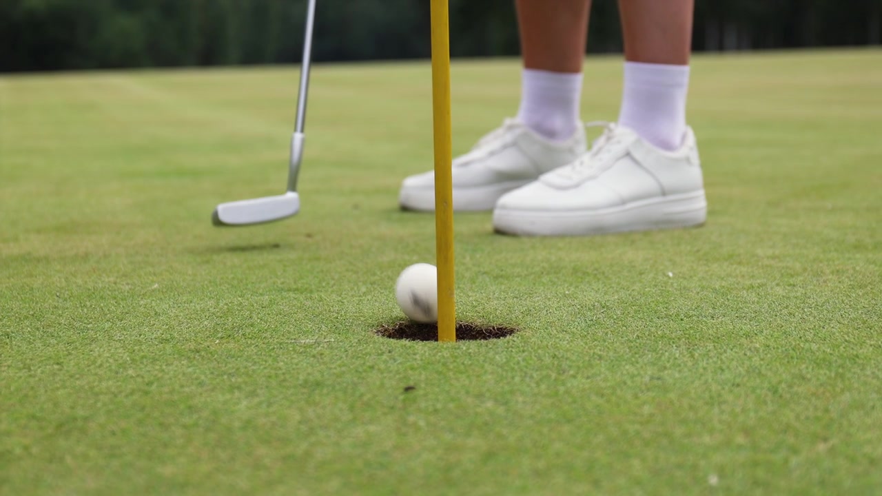 Detailní záběr golfového míčku patovaného do jamky