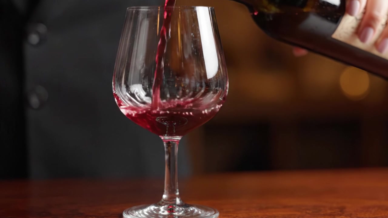 Uma Servida Sofisticada: Capturando a Arte de Servir Vinho Enquanto um Copo é Preenchido com Vinho Tinto Rico, Exibindo Perfeitamente a Cor Vibrante e a Textura do Vinho