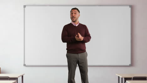 mature male teacher in classroom standing in front of board teaching lesson in school