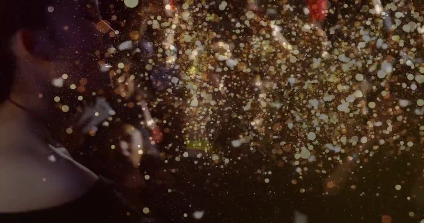 Left woman watching concert while stage ejecting gold glitter for finale, glitter blurring phones