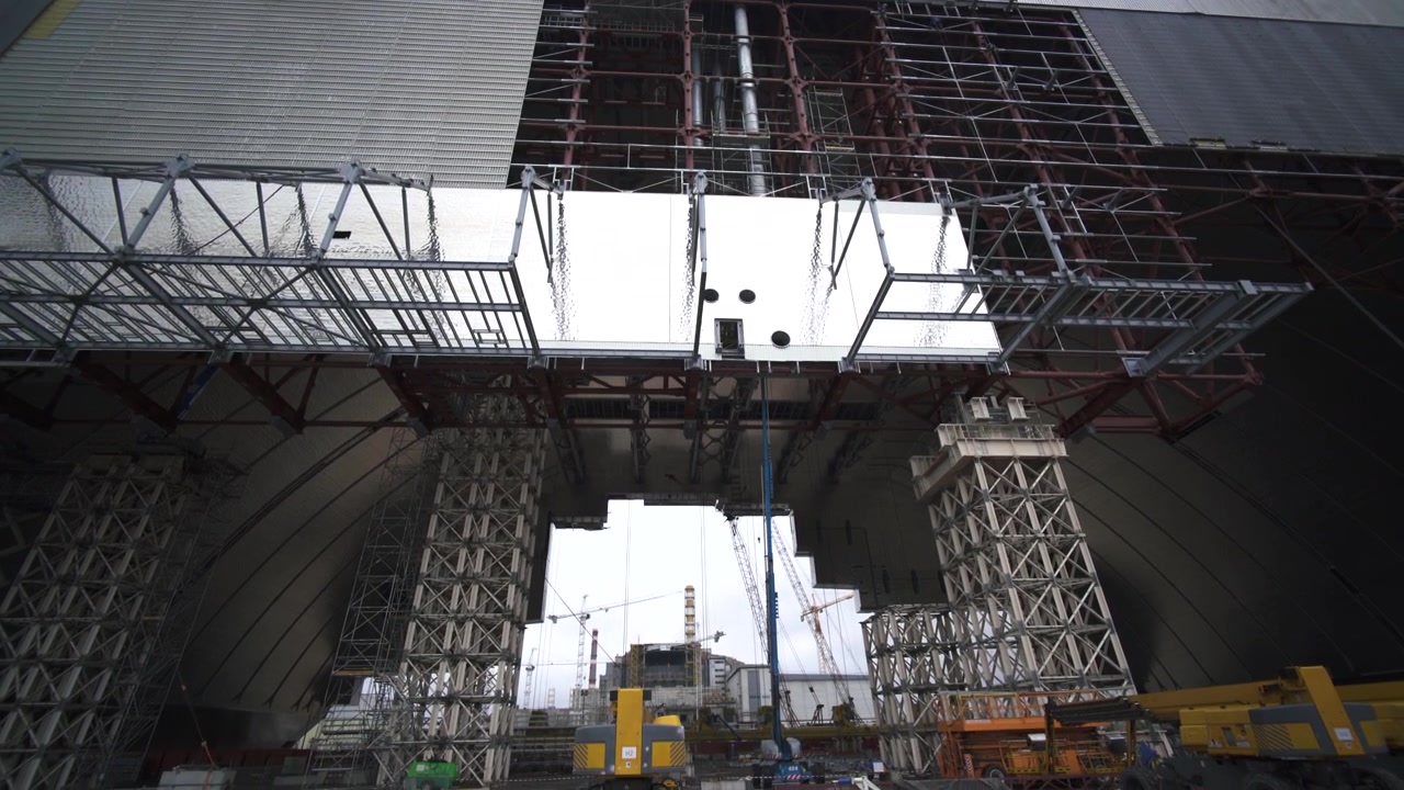 A tilt down shot shows the massive arch structure of Chernobyl under construction.