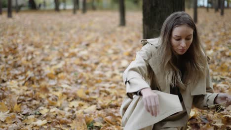 a woman collects fallen yellow leaves in the autumn park, slow motion