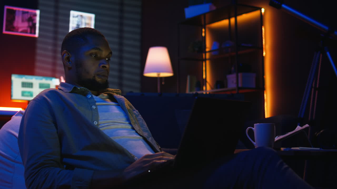 Vertical Video Skilled african american man multitasking on laptop in cool living room
