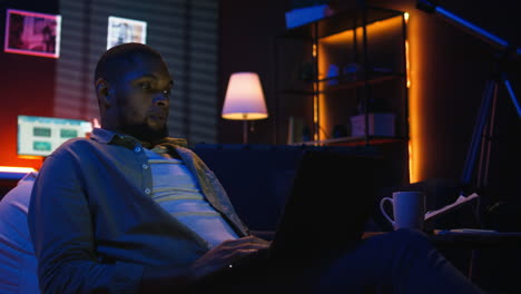 vertical video skilled african american man multitasking on laptop in cool living room