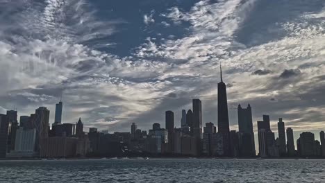 a wide shot of the chicago skyline with dramatic clouds rolling above the skyscrapers, viewed from lake michigan's edge.