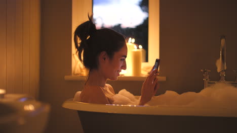 woman relaxing in a bubble bath with phone