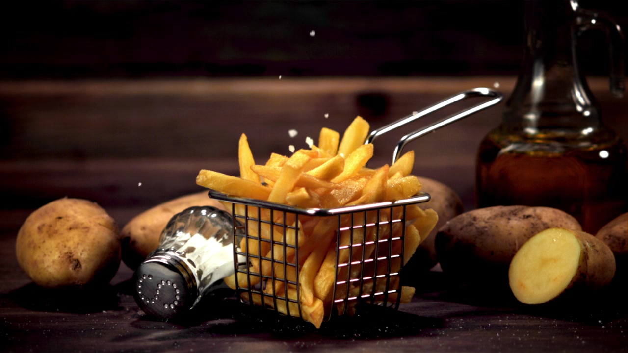 Salt Falling on Crispy Golden French Fries in Slow Motion