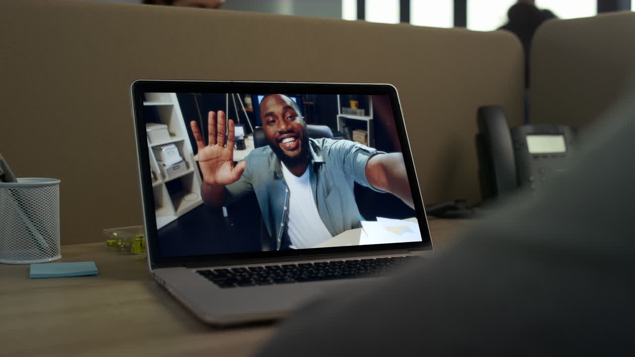 Office clerk video call laptop greeting with colleague close up