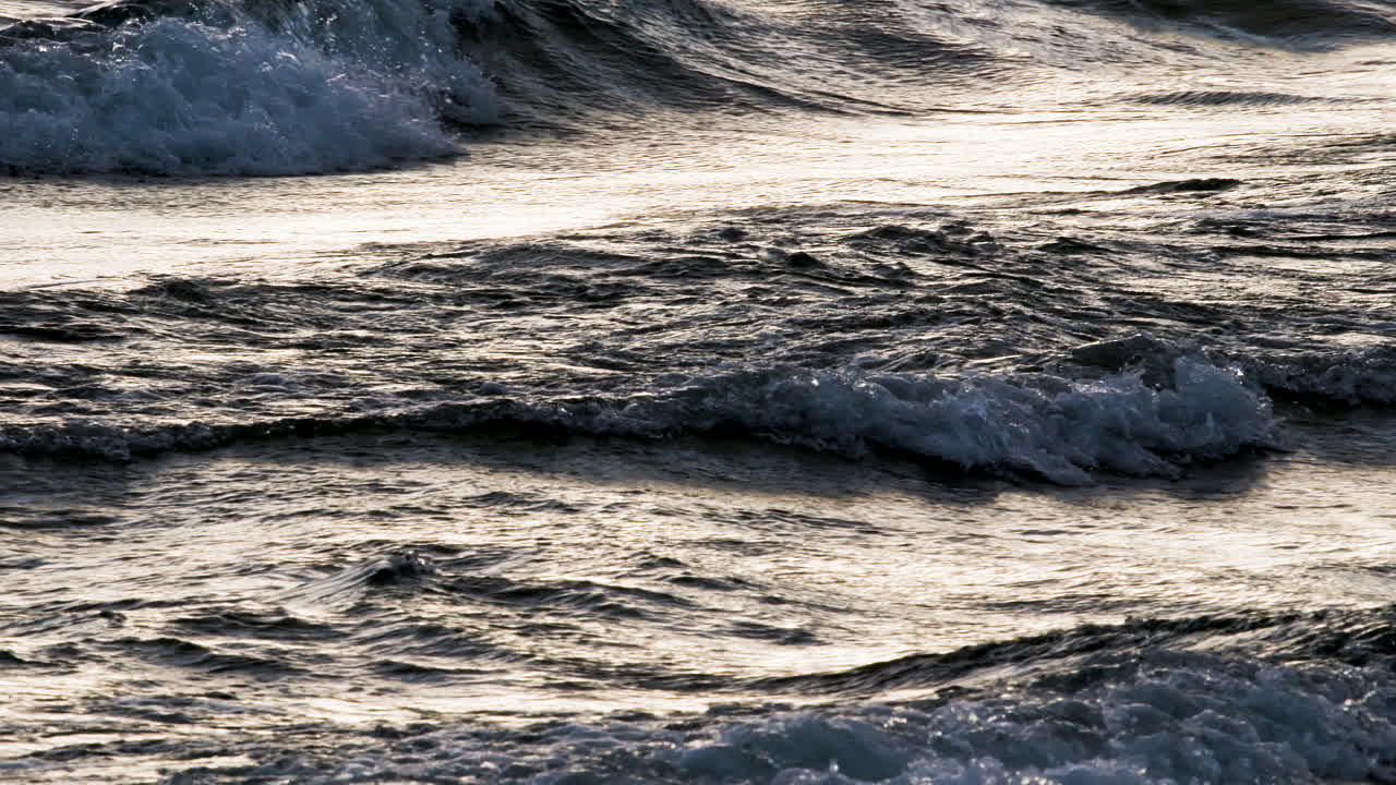 Waves rolling in slow motion backlit by sunlight