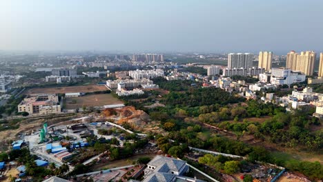 aerial view of chennai's urban sprawl, omr area. shows mixed development: modern high-rises, ongoing construction, green patches, and older structures.