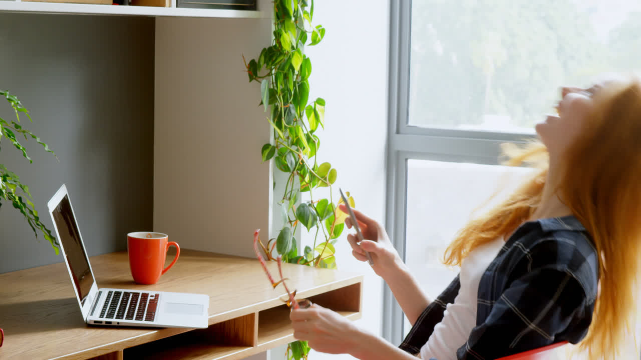mujer ejecutiva usando portátil y teléfono móvil en la oficina 4k