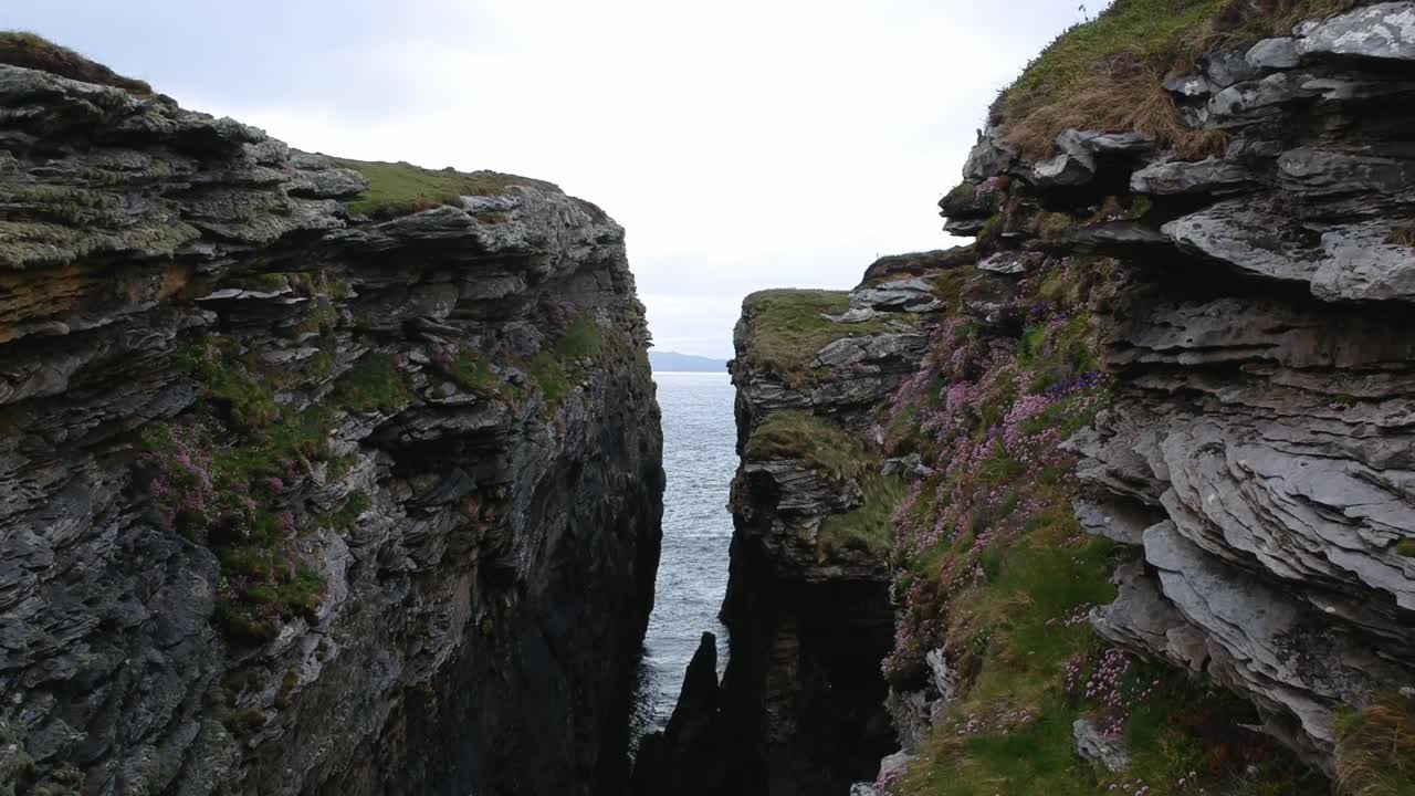 Fly-through push-forward drone shot of ocean cliffs