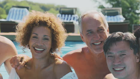 Portrait-Of-Multi-Cultural-Group-Of-Senior-Friends-Relaxing-In-Outdoor-Pool-On-Summer-Vacation