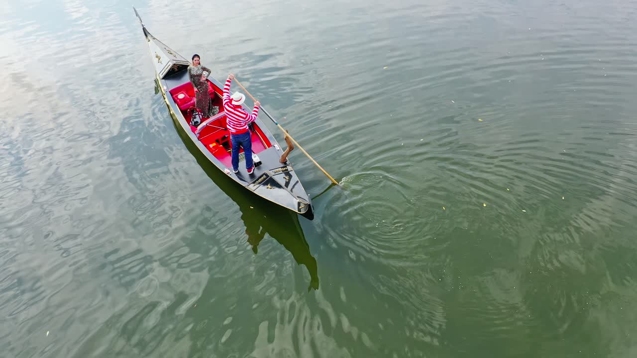 Beautiful woman riding in gondola. Luxury woman travels in a boat along the river in Venice, Italy. Aerial view.