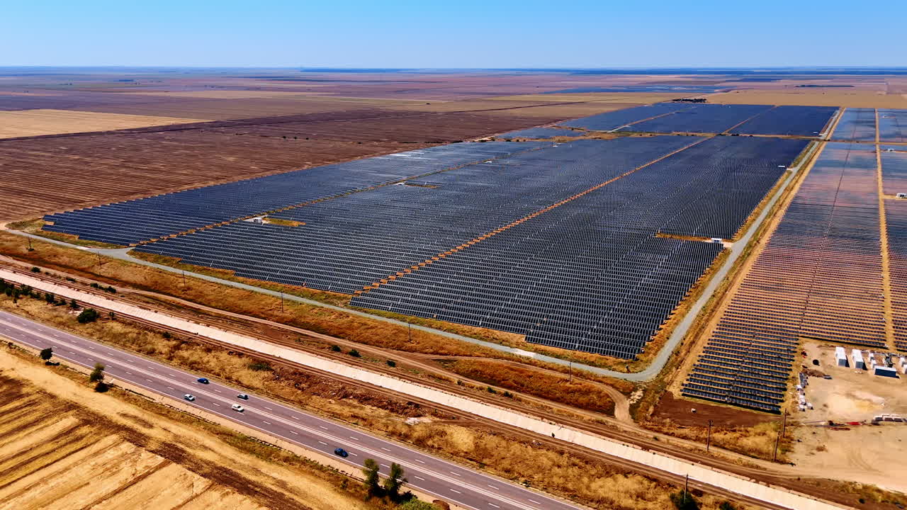 Solar power plant across vast desert plain. Photovoltaic solar farm covers large desert plain with panels reflecting sunlight