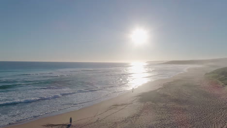 Aerial-shot-of-fishermen-standing-along-a-beach-at-sunset-in-South-Australia