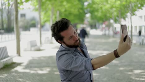 hombre barbudo fotografiando con un teléfono inteligente al aire libre