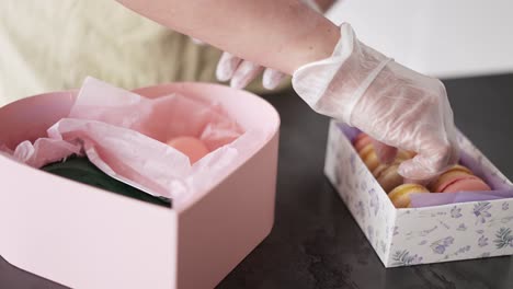 Female-hands-puts-macaroni-in-gift-box-at-kitchen