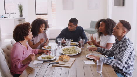 elevated view of black family sitting at dinner table talking as they eat together, close up