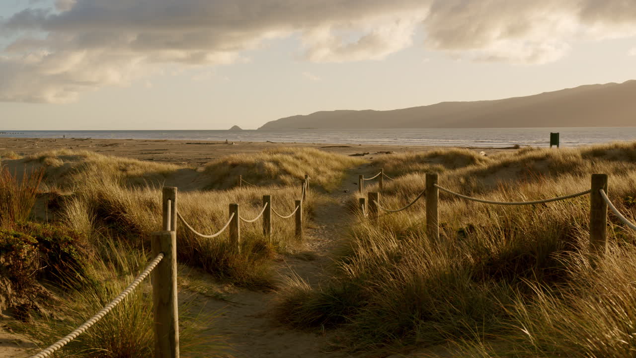 Panning to a roped path on a beach at sunset, Waikanae beach, New Zealand
