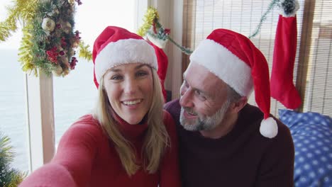 Happy-caucasian-mature-couple-making-video-call-in-room-full-of-christmas-decorations