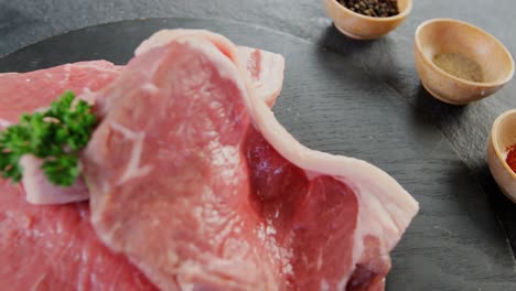 sirloin chop and bowls of spices on concrete background