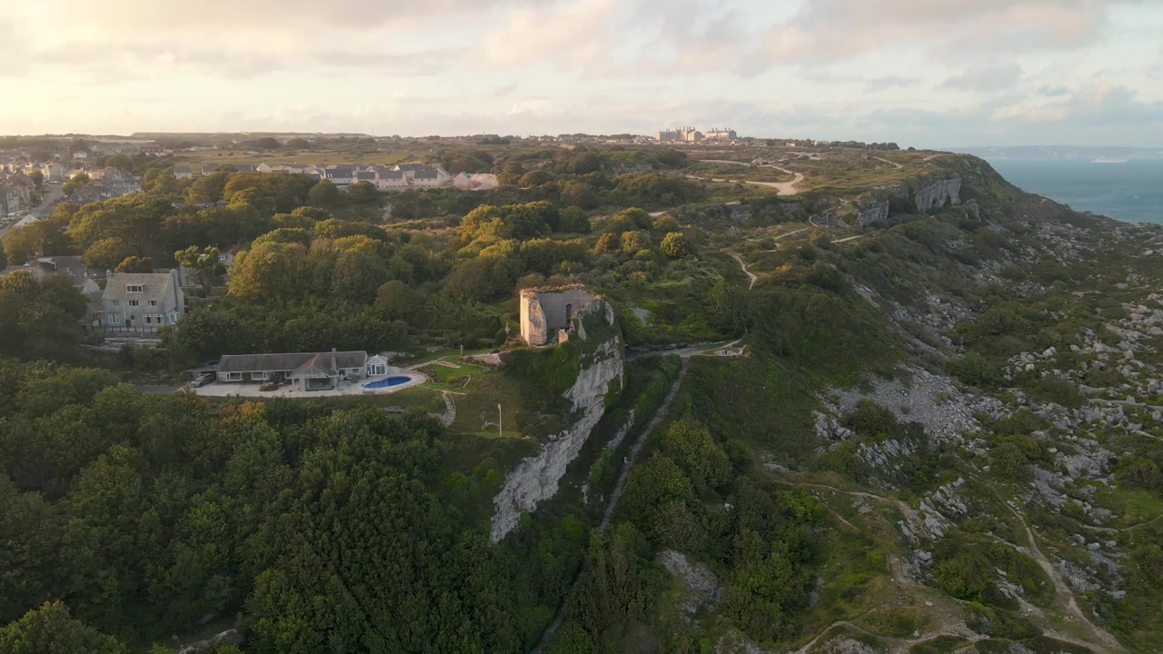 İngiltere'deki Portland, Dorset kayalıklarının tepesinde yer alan eski bir kale kalıntısına doğru ilerleyen bir drone'un güzel bir gün batımında çekilmiş 4K görüntüleri.