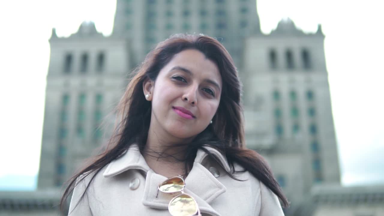 retrato de una mujer sonriendo a la cámara con el palacio de la cultura y la ciencia en el fondo en varsovia, polonia
